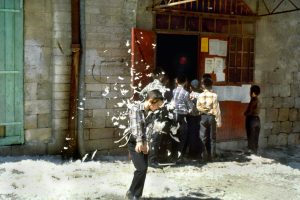 CHILDREN PLAYING WITH CHICKEN FEATHERS NEAR A BUTCHER SHOP, AT JERUSALEM'S MEA SHE'ARIM MARKET.ילדים משחקים בנוצות עופות ליד חנות למכירת בשר, בשוק במאה שערים בירושלים.