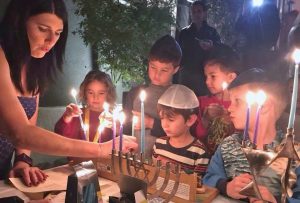 Audrey lighting hannukah candles with kids